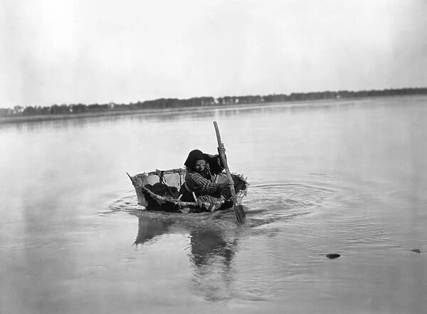 MANDAN BULL BOAT, c1908. A Mandan Native American woman paddling a bull boat