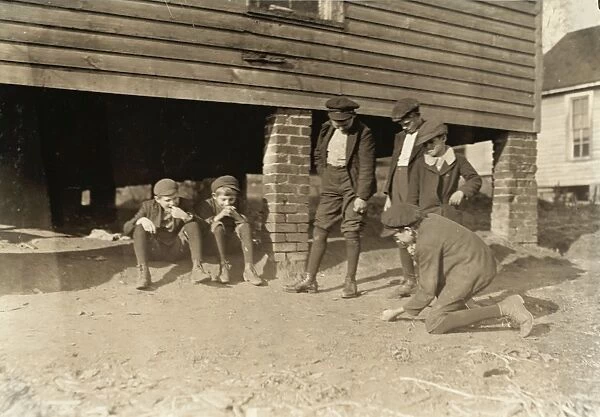 MARBLE GAME, 1908. Group of boys shooting a game of marbles outside the cotton
