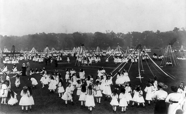MAY DAY, c1910. A group of schoolgirls dancing in a field on May Day, some holding