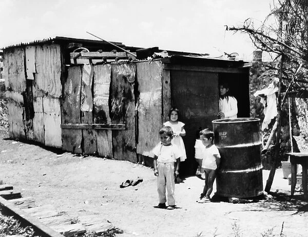 MEXICO: POVERTY, 1964. Children gathered around the entrance of a shack next to