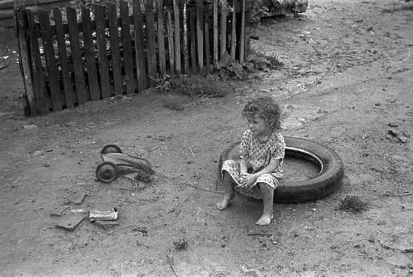MIGRANT CAMP, 1938. A young girl sitting in a tire in Circlevilles Hooverville