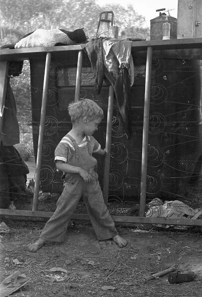 MIGRANT CHILD, 1936. Son of destitute migrant worker playing with the coils of