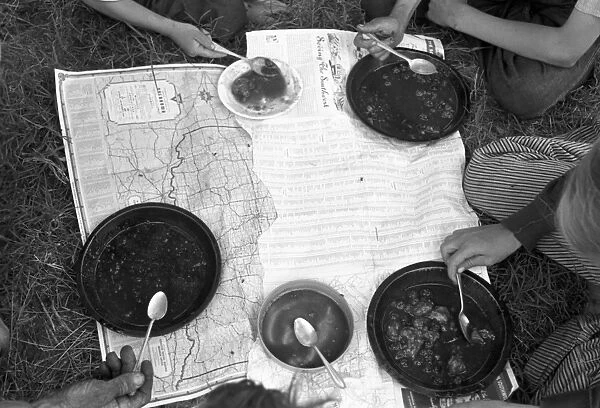MIGRANT FAMILY, 1939. The lunch of a migrant family with a map as a tablecloth