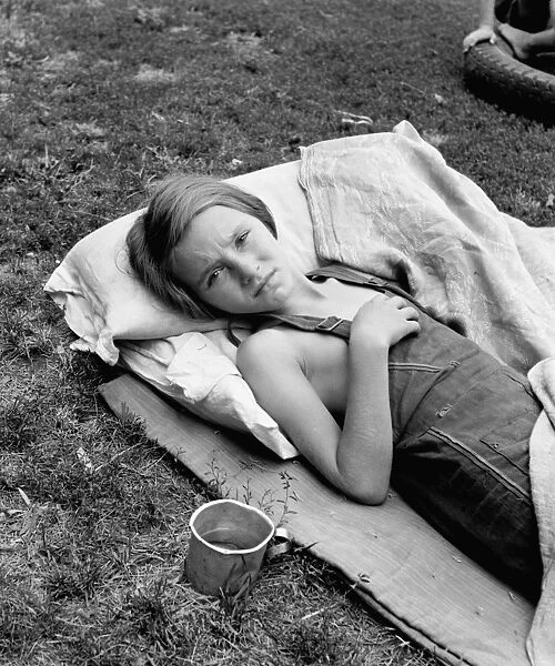 MIGRANT GIRL, 1930 S. A sick migrant girl resting on a makeshift bed outside, Yakima Valley