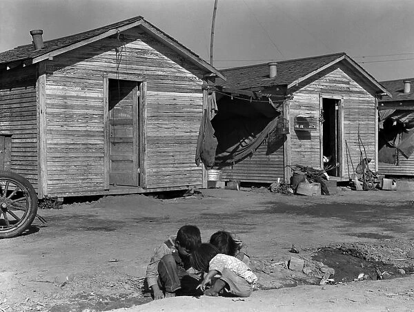 MIGRANT HOUSING, 1936. Children playing in front of housing for migrant cotton
