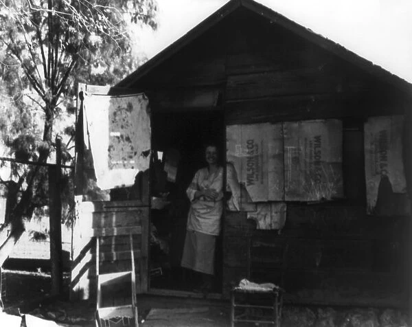 MIGRANT WORKER, 1935. Migrant women standing in doorway of the shack at a camp