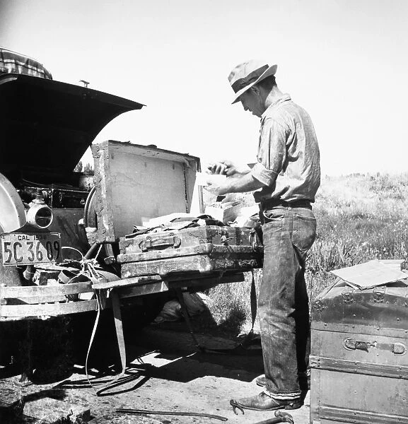 MIGRANT WORKER, 1938. Migrant worker sorting luggage in San Joaquin Valley, California
