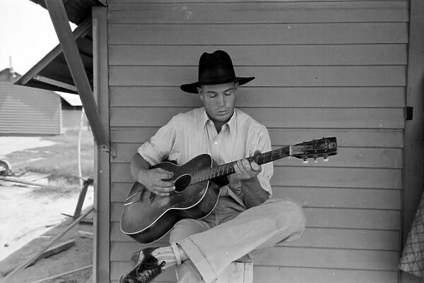 MIGRANT WORKER, 1940. A migrant worker playing guitar in the Agua Fria Labor Camp, Arizona