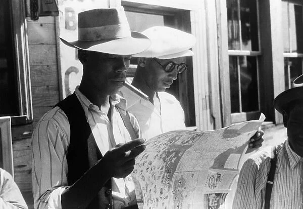 MIGRANT WORKERS, 1940. Florida migrants studying a road map before leaving Elizabeth City