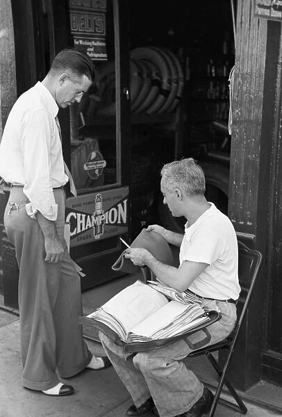 MISSOURI: SALESMAN, 1938. Tire salesman showing a rubber inner tube to an auto supply storekeeper