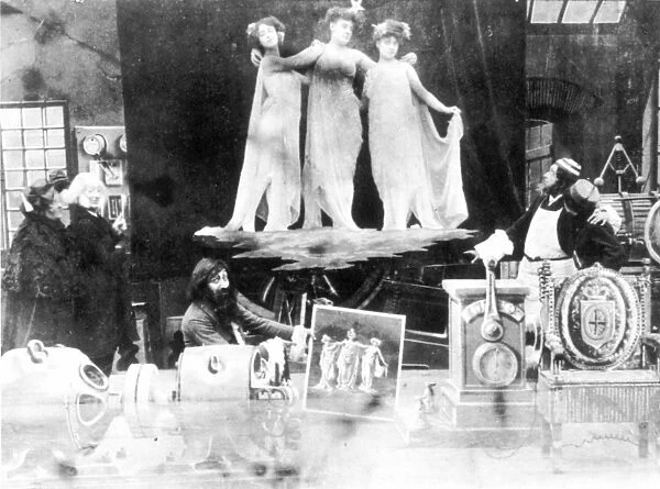 MÔÇ░LI╦åS FILM, 1907. Three dancers from the Folies Bergre, whose photograph has been transmitted by wireless, symbolically float above the inventor who displays the resulting print, in a scene from the 1907 film Long-Distance Wireless Photography, by Georges M lis