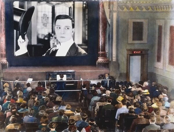MOVIE THEATER, 1920s. Interior of an unidentified New York City motion picture theatre showing a film with Buster Keaton. Oil over a photograph, 1920s