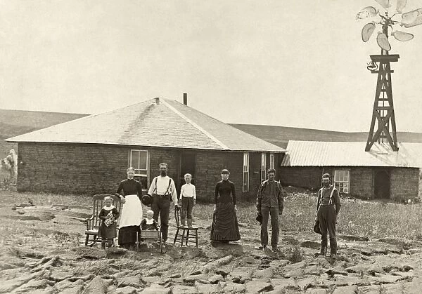 NEBRASKA: SETTLERS, c1885. Family of homesteaders, photographed outside of their sod house with a windmill on the roof of the adjoining building in Custer County, Nebraska. Photograph by Solomon D. Butcher, c1885