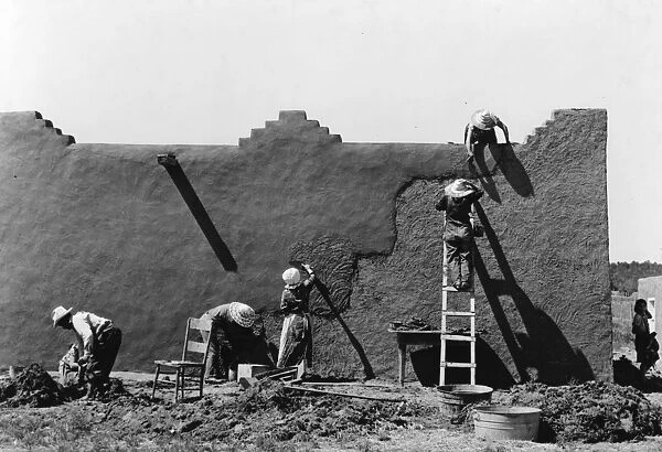 NEW MEXICO: ADOBE, 1940. Latin-American women replastering an adobe house in Chamisal, New Mexico