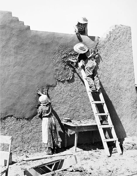 NEW MEXICO: ADOBE HOUSE. Replastering an adobe house at Chamisal, New Mexico. Photograph