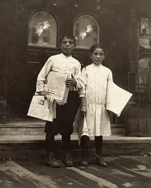 NEWSBOY AND NEWSGIRL, 1910. A Newsboy and newsgirl selling newspapers around saloon