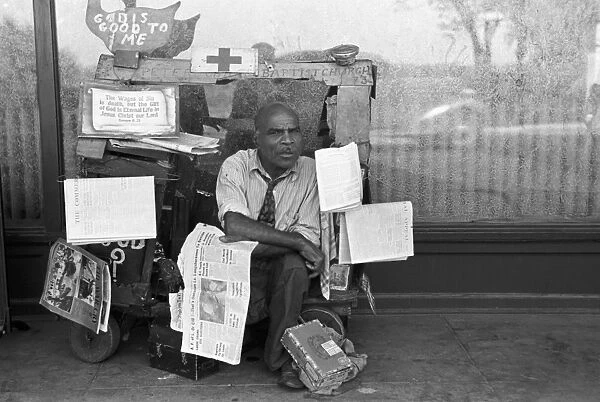 NEWSPAPER PEDDLER, 1938. Vendor selling newspapers on the sidewalk, Memphis, Tennessee