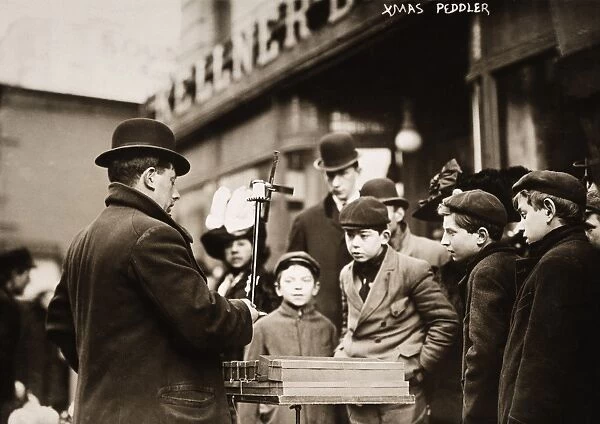 NYC STREET PEDDLER, 1910. A New York City street peddler demonstrating whirligigs