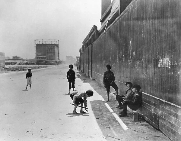 NYC: TENEMENT LIFE. Boys playing a game near tenements in New York City