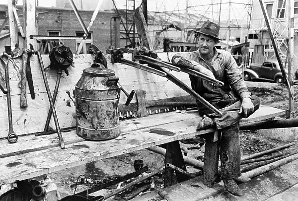 An oil field worker resting on a pipe wrench at Kilgore, Texas. Photograph by Russell Lee, April 1939