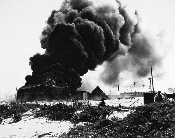 Oil tanks burn after being attacked by Japanese warplanes at the U. S. Naval Air Station on Sand Island, Midway atoll, during the Battle of Midway, 4 June 1942