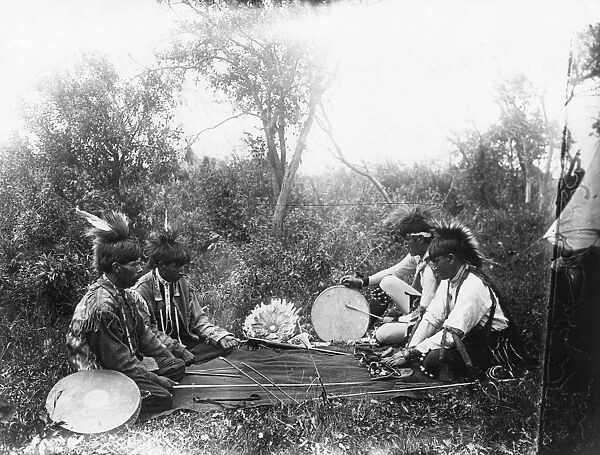 OJIBWA GAME, c1910. Four Ojibwa Native American men playing a moccasin game, in