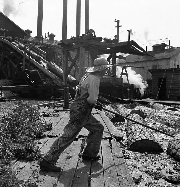 OREGON: SAW MILL, 1939. A pond monkey worker guides the direction of logs