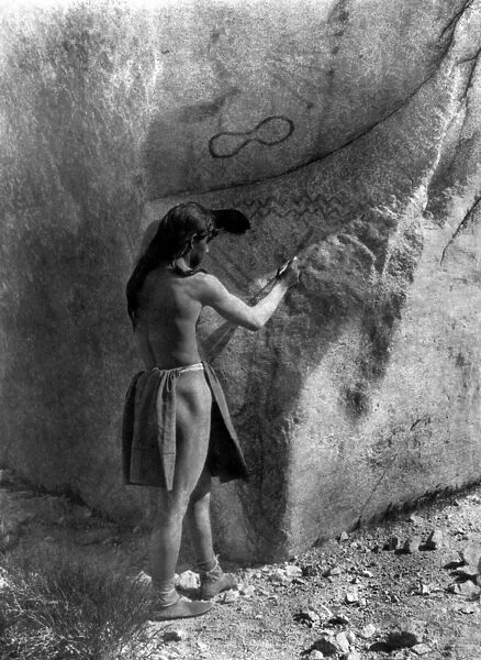 PAIUTE PAINTER, c1924. A Paiute Native American man painting on a boulder