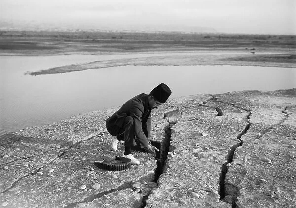 PALESTINE: EARTHQUAKE. A Palestinian man uses his rifle to measure the deep land