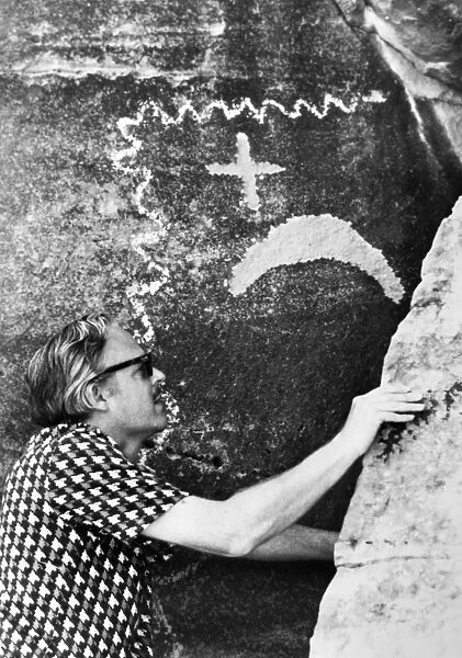 PETROGLYPH: SUPERNOVA. Dr. John Brandt of NASA examines an ancient Native American petroglyph which he believes commemorates the sighting of the supernova (exploding star) which created the Crab Nebula in 1054 A. D. The petroglyph is near the ruins of the village of the Great Kivas, near Zuni, New Mexico. Photograph, 1975