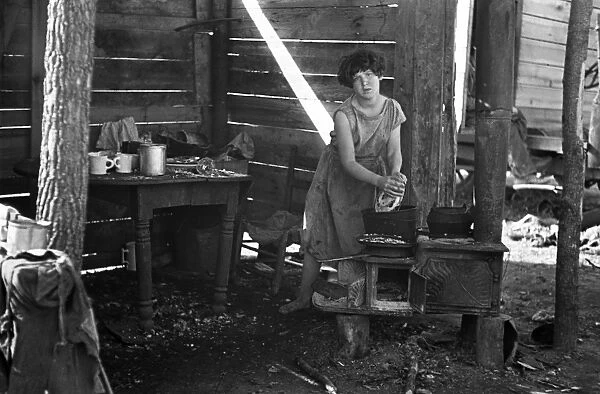 POVERTY: LEAN-TO, 1936. A twelve-year old girl cooking for her family in a lean-to kitchen