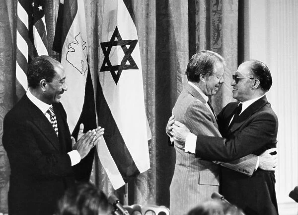 President Anwar Sadat of Egypt applauds as U. S. President Jimmy Carter embraces Prime Minister Menachem Begin of Israel during a press conference September 1978