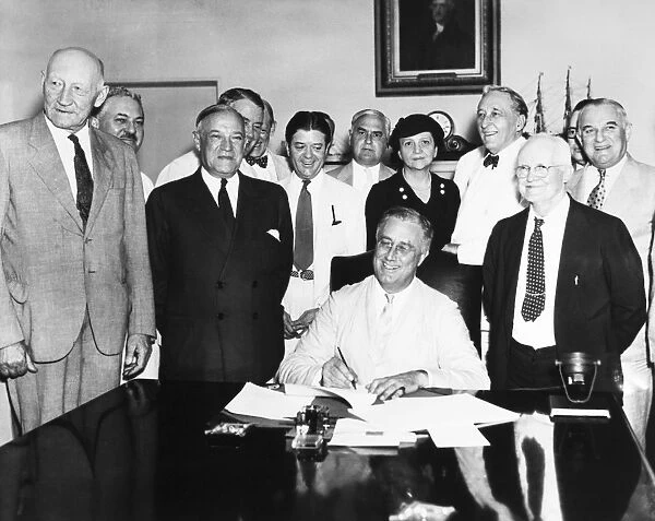 President Franklin D. Roosevelt signing the Social Security Act in the Cabinet Room of the White House, 14 August 1935, flanked by the bills co-authors (in dark suits), Robert F. Wagner of New York (left) and David J. Lewis of Maryland. Standing directly behind the President is Secretary of Labor Frances Perkins