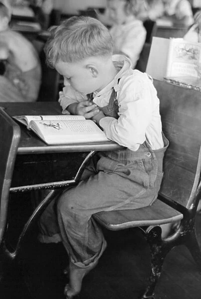 SCHOOLBOY, 1938. Children studying in an elementary school classroom for migrant