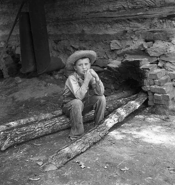 SHARECROPPER, 1939. Ten year-old son of a sharecropper resting on a log after working