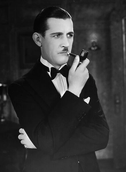 SILENT FILM STILL: SMOKING. Charley Chase (1893-1940) with pipe, 1928