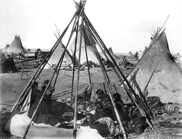 SIOUX ENCAMPMENT, 1891. Oglala Sioux women and children seated inside an uncovered tipi frame