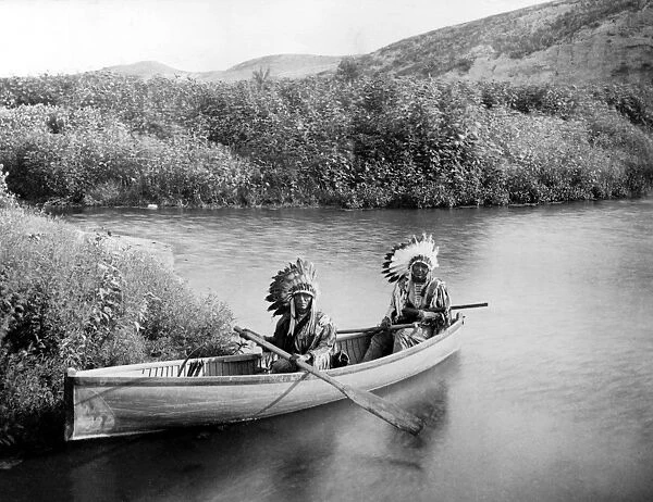 SIOUX HUNTERS, c1902. Two Native American men hunting in a canoe on a river. Photograph by John Alvin Anderson, c1902