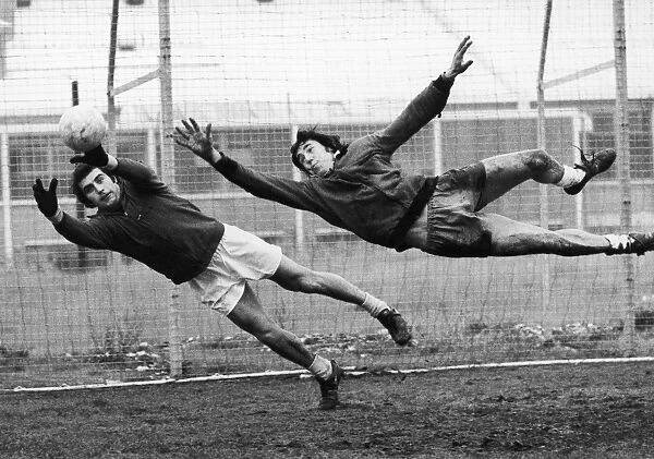 SOCCER GOALIES, 1974. English goalkeeper Peter Shilton (left) and Gordon Banks both jump to block a goal during a work-out at Stoke City, November 1974
