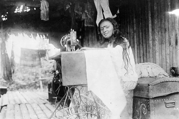 SOUTH AMERICAN INDIAN. A South American Indian woman using a sewing machine in her hut