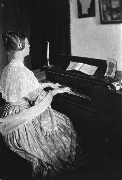 SPINET PIANO, c1900. Woman playing a spinet piano. Photographed by Frances S. Allen
