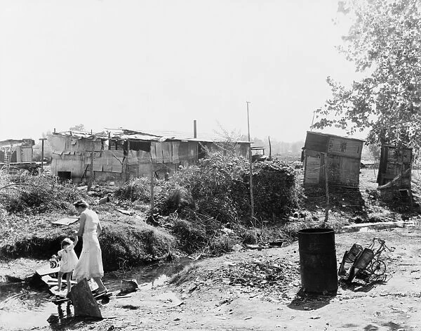 SQUATTERS CAMP, 1936. A mother and child crossing a stream in a squatters camp