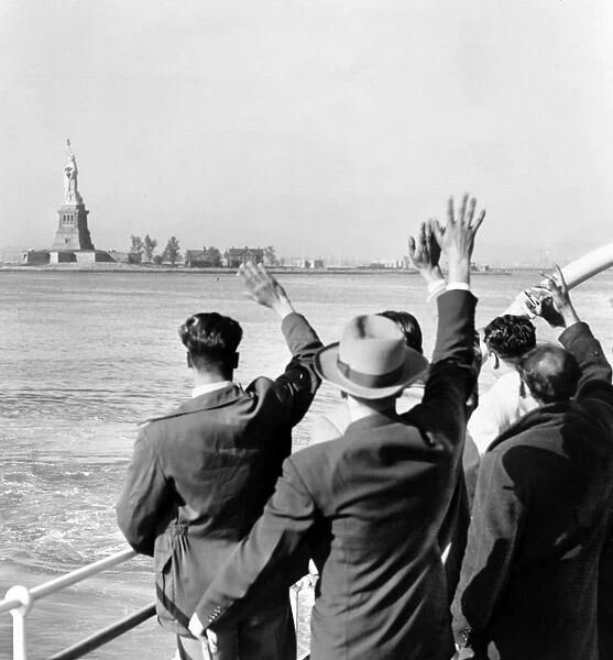 STATUE OF LIBERTY. Part of a group of illegal immigrants waving goodbye to the Statue of Liberty from the Coast Guard cutter that took them from Ellis Island to the Home Lines ship Argentina in Hoboken for deportation. Photographed by Al Ravenna, c1952