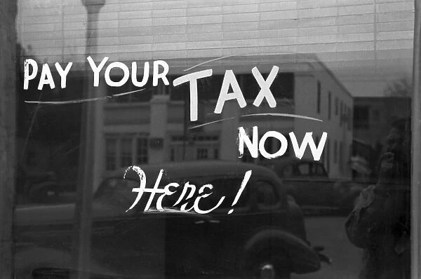 STOREFRONT SIGN, 1939. Pay Your Tax Now, Here!, painted on a storefront window in Harlingen, Texas. Photograph by Russell Lee, February 1939