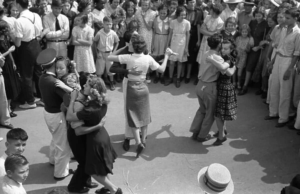 STREET DANCE, 1938. Young couples slow dance in the street at the National Rice Festival