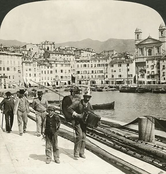 STREET MUSICIAN, 1907. An Italian street musician on the waterfront in Bastia, Corsica, France