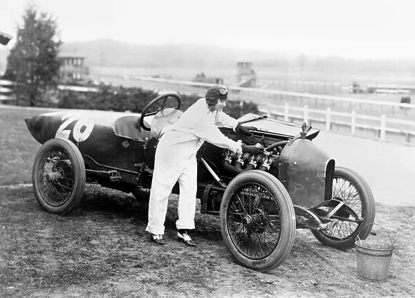 STUTZ RACECAR, 1916. A woman working under the hood of a Stutz Weightman Special