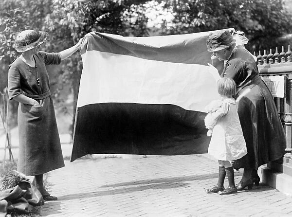 SUFFRAGETTES, c1915. Two suffragettes show their banner to a young girl. Photograph