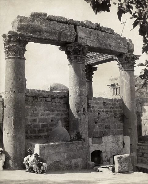 TEMPLE RUINS. Two Middle Eastern men seated in front of temple ruins