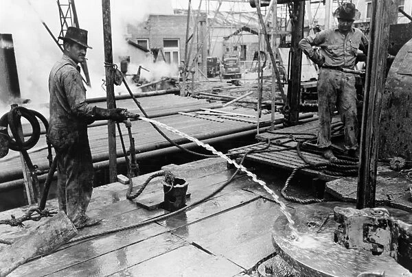 TEXAS: OIL WELL, 1939. Workers cleaning off the rotary table with water at a oil well in Kilgore